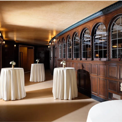 A hallway features round tables with white tablecloths and small floral arrangements, surrounded by dark wood paneling and arched windows.
