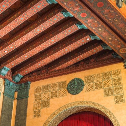 The hand-painted gilded ceilings of red, gold, cream, and green patina highlight the spectacular architecture throughout the main theatre.