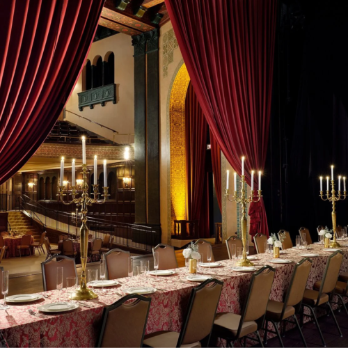 A dramatic view from the Bonstelle stage, set with an extended dining table overlooking the main theatre.